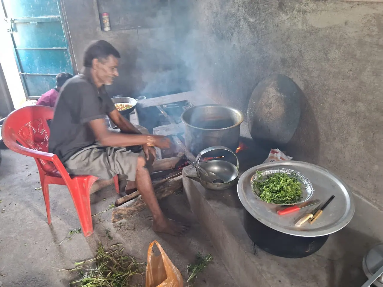 A cook preparing a meal over a wood fire in the school kitchen.